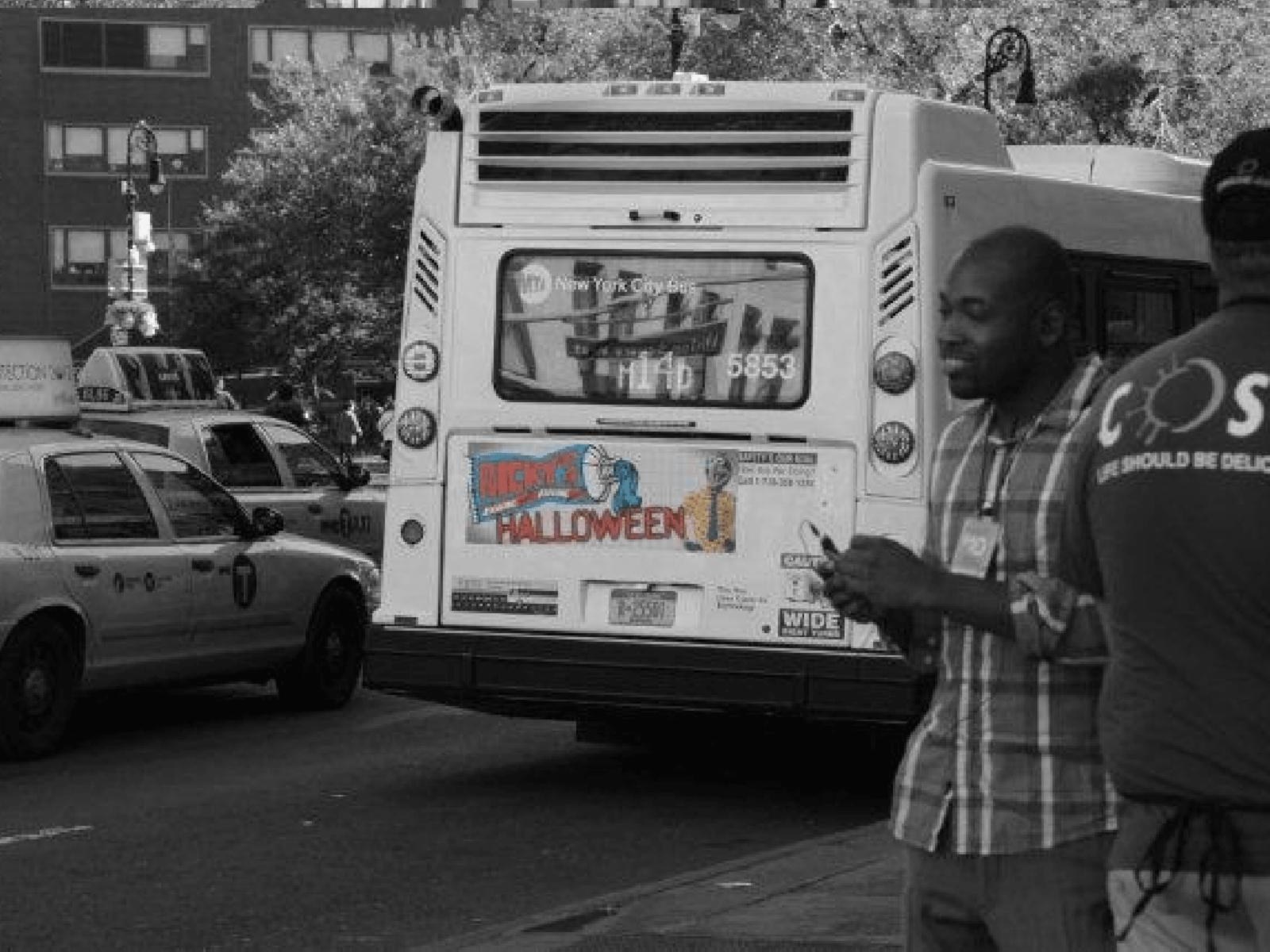 Ricky’s Halloween bus tail beside taxis on a Manhattan street