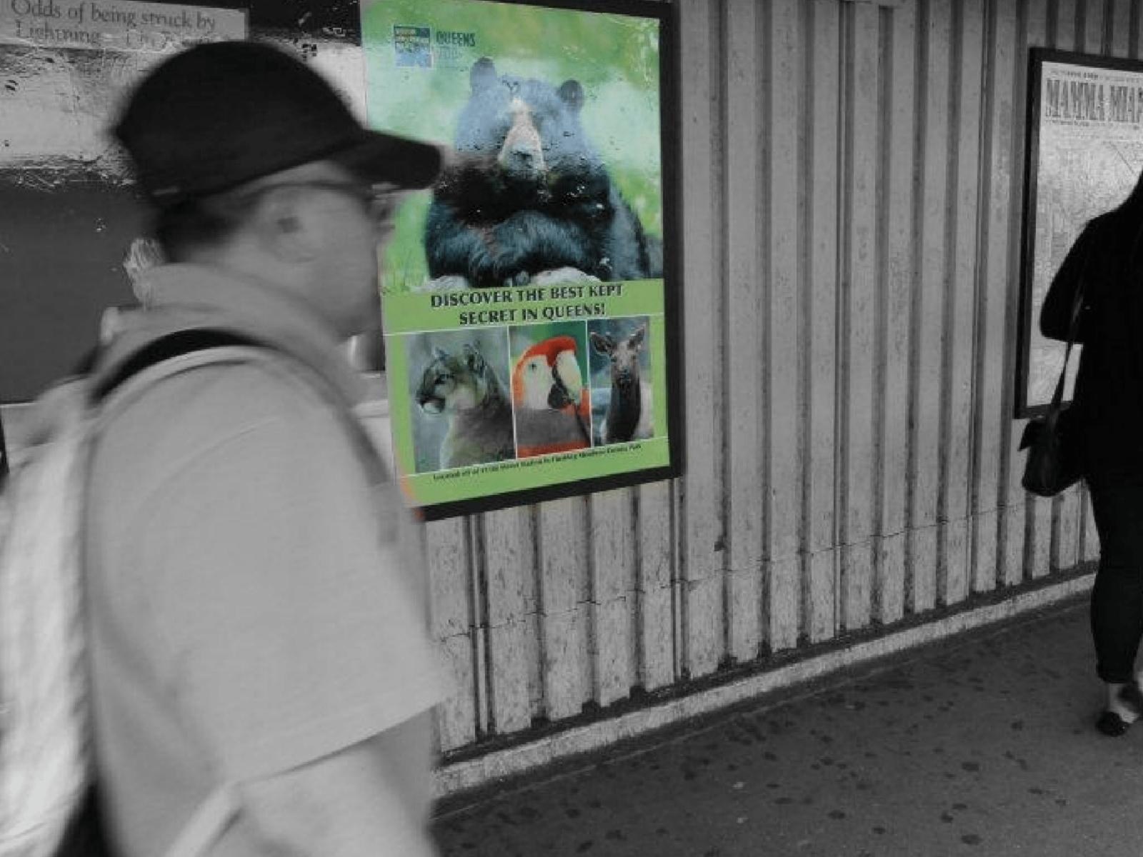 Rider walking past the Queens Zoo one-sheet on a subway platform